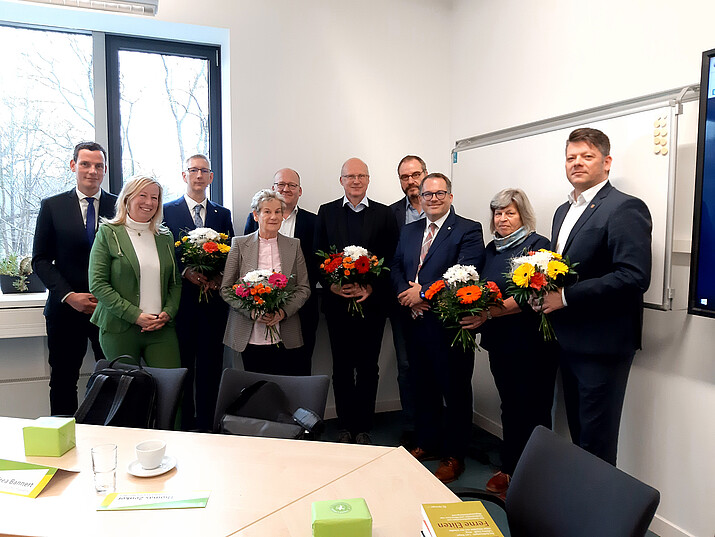 The University Council and the Rectorate stand together as a group in the seminar room and smile into the camera.