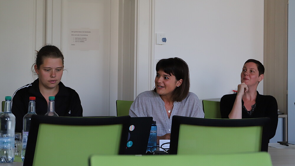 Three participants at the first meeting of the Center for Gender Equality, Inclusion, Women's and Diversity Studies sit and discuss at the table in the Senate Hall of the HSZG.