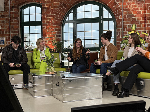 HIT participants sit on the green sofas in the studio and chat.