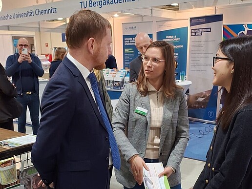 The Saxon Minister President in conversation with the student advisor and Zhaniya at the HSZG stand.