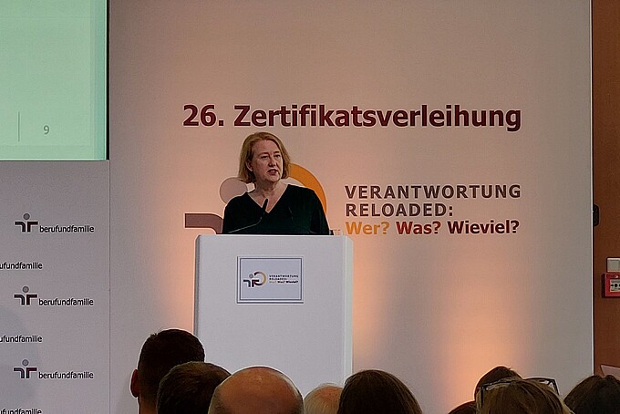 The Federal Minister for Family Affairs stands on the stage at the lectern and gives a speech.
