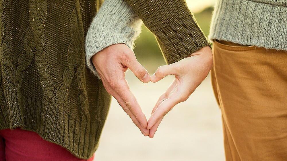 Two people form a heart with their hands.