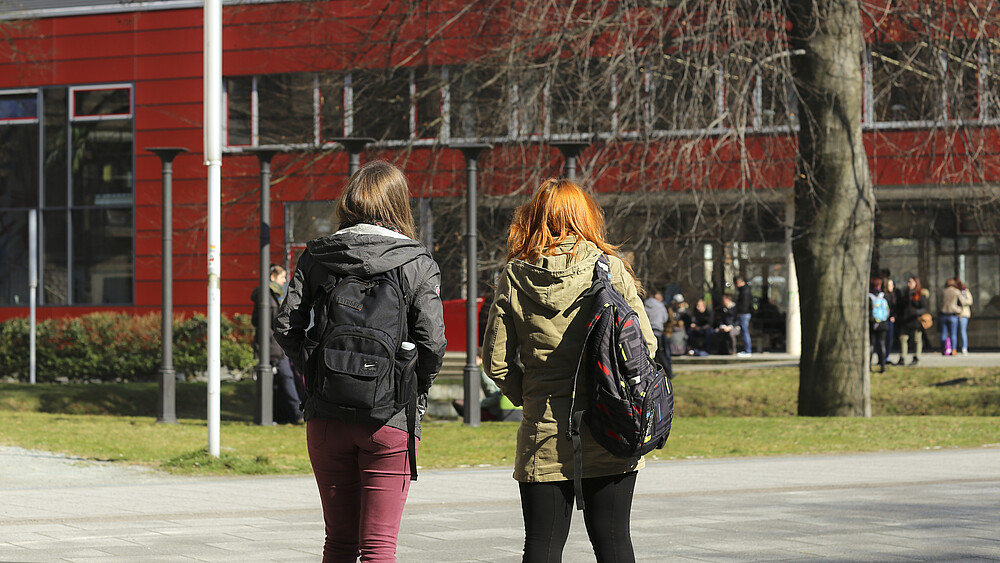 Two students in front of a building of the HSZG