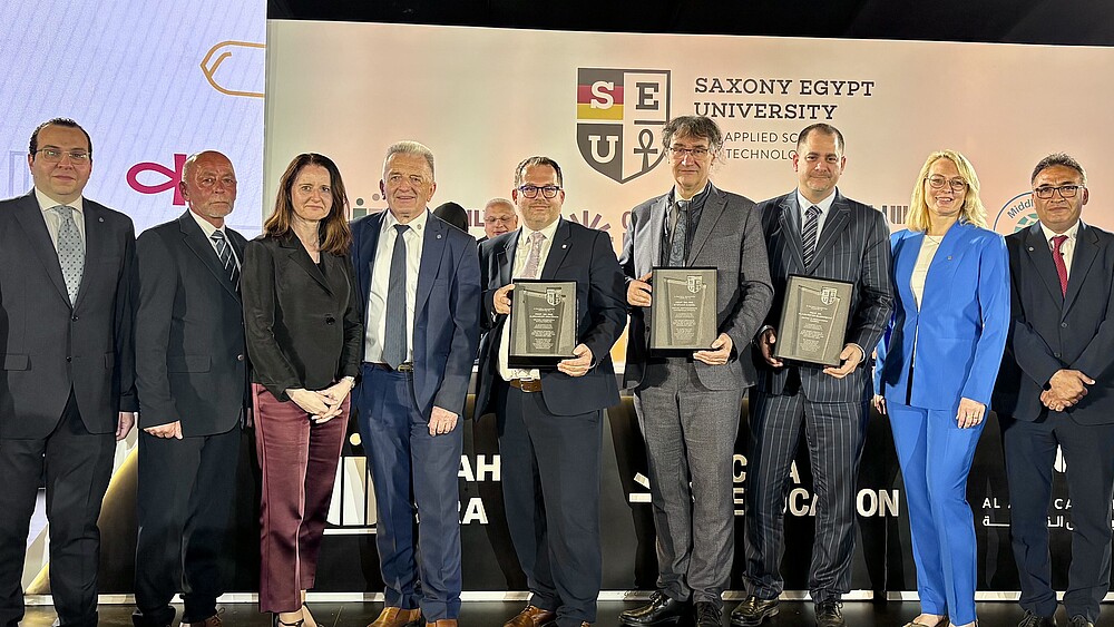 The Minister President and representatives of Saxony's higher education sector show their signed agreements to the camera on the podium.