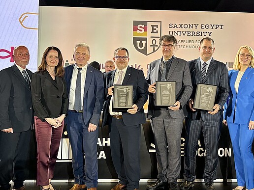 The Minister President and representatives of Saxony's higher education sector show their signed agreements to the camera on the podium.