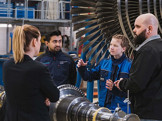 Four people in front of an industrial turbine