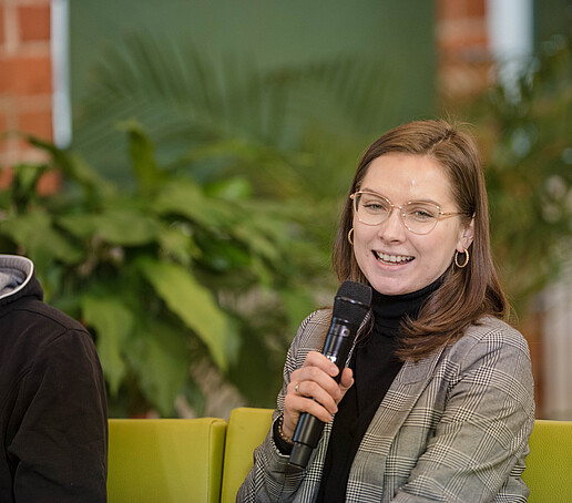 Alina Bulcsu with microphone on the talk sofa