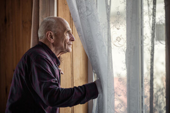 Älterer Mann schaut aus dem Fenster
