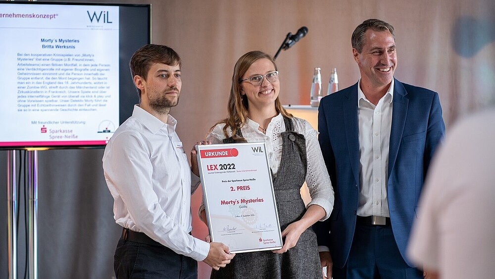 At the LEX award ceremony, the runners-up hold their certificates up to the camera.