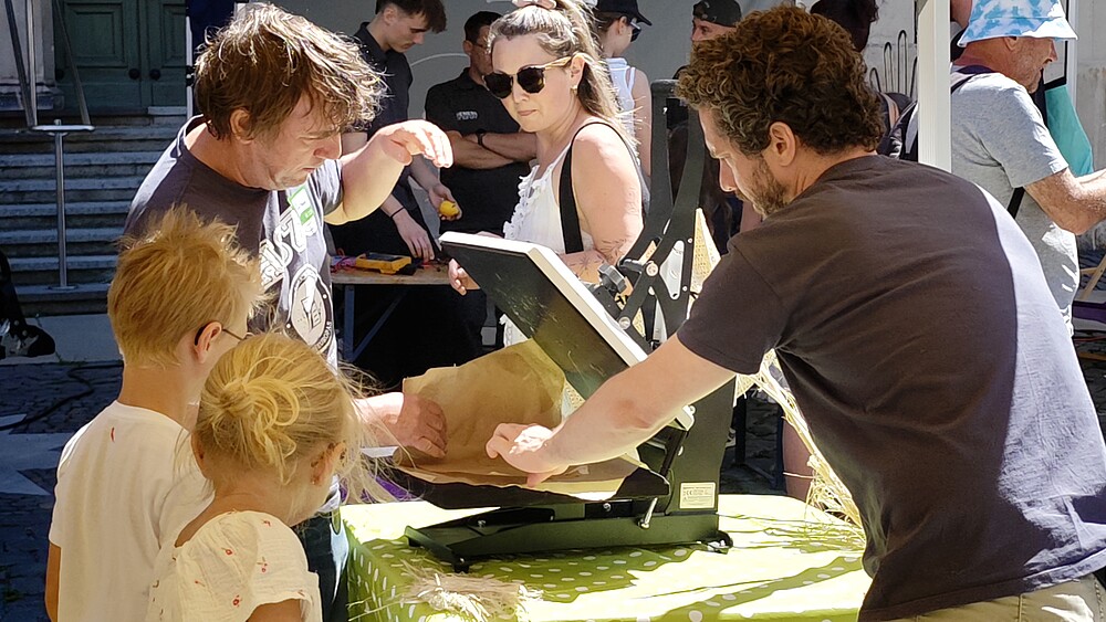 Kinder und Erwachsene probieren an einem Mitmachstand der HSZG beim Zittauer Stadtfest ein technisches Exponat aus.