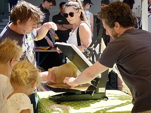 Children and adults try out a technical exhibit at an HSZG hands-on booth during the Zittau City Festival.
