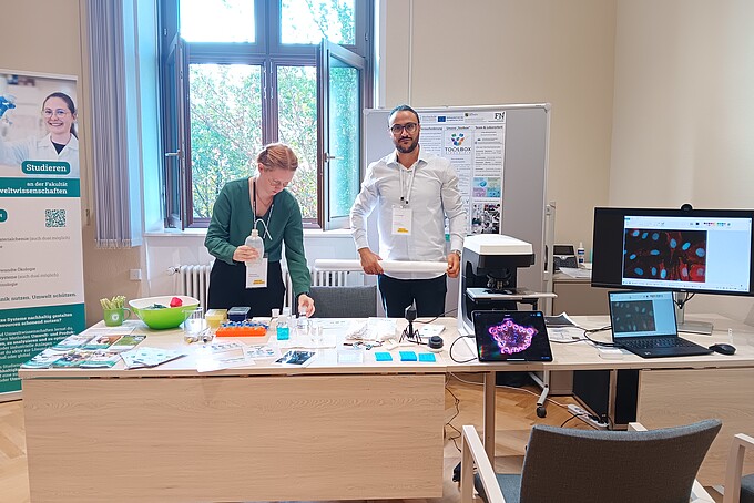 Pia Schubert und Ali Al Hamad bereiten am HSZG-Stand Materialien für Pipettierübungen und Mikroskopie vor.