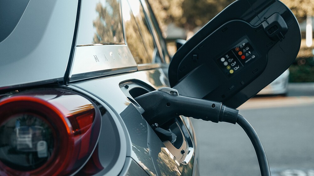 An electric car with the protective cover open, the charging cable is connected.