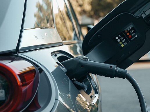 An electric car with the protective cover open, the charging cable is connected.