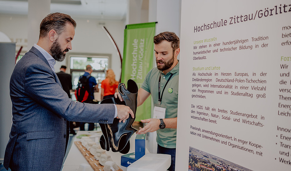 Foto: SMWK Der Wissenschaftsminister bekommt vom HSZG-Mitarbeiter ein 3D-gedrucktes Skoliose-Korset gereicht.