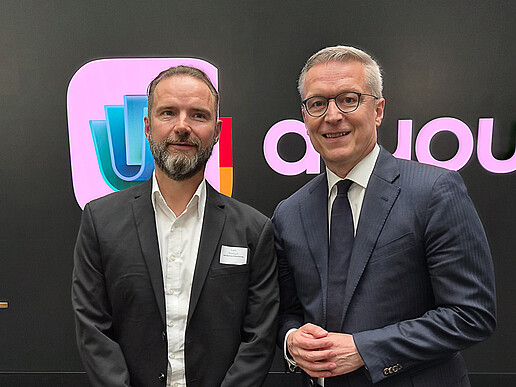 Lars Rönisch and Federal Minister for Digital Affairs Dr. Karsten Wildberger are standing in front of a wall featuring the logo of the digital identity wallet d-you.
