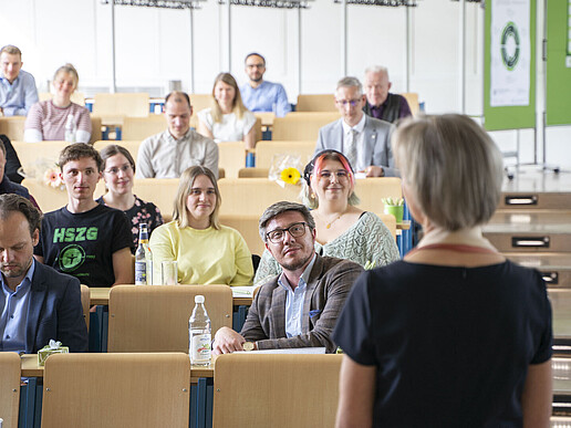 Die Prorektorin steht zu vollbesetzten Sitzreihen im Hörsaal zugewandt.