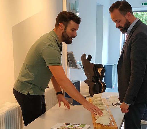 An HSZG employee presents the O-Mask to Science Minister Gemkow at the stand.