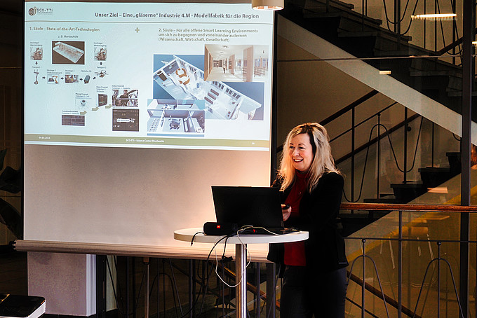 Prof. Dr. Sophia Keil stands at a high table with her laptop open and gives a lecture.
