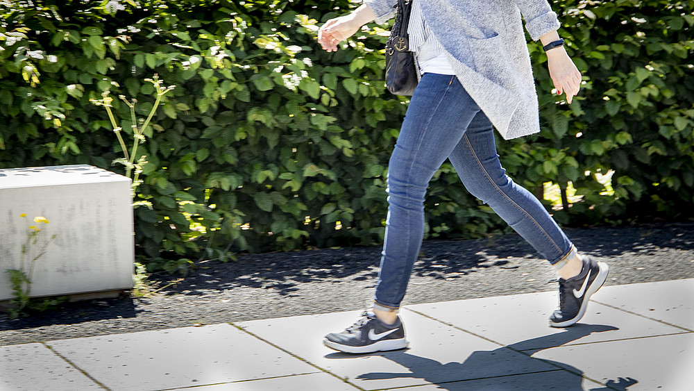 Auf dem Fotos läuft eine Frau. Zu sehen ist der Unterkörper mit Fokus auf die Beine und Schuhe.