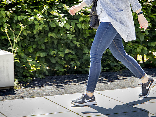 The photo shows a woman walking. You can see the lower body with a focus on the legs and shoes.