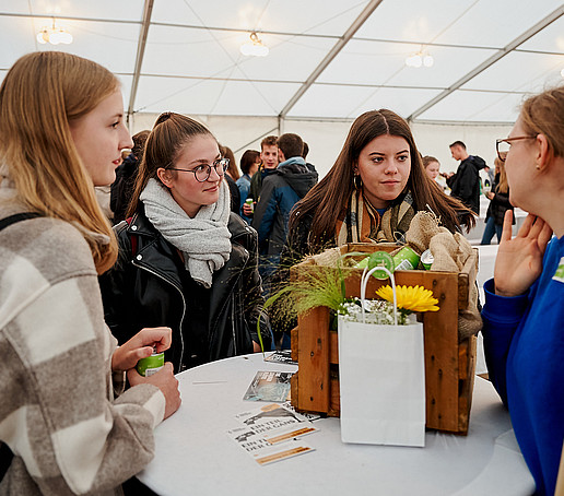 Neuimmatrikulierte besprechen sich an einem Fakultätsstand.