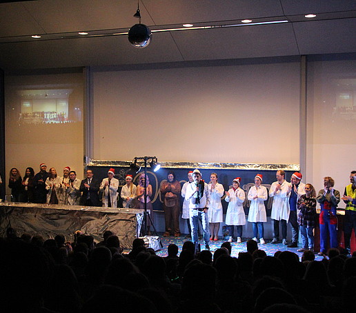 The entire show lecture team stands as a group in a row on the stage and applauds.