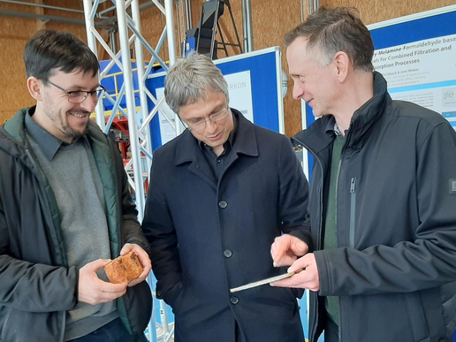 Three men look at materials for sustainably produced wind turbines in the Lander hall.