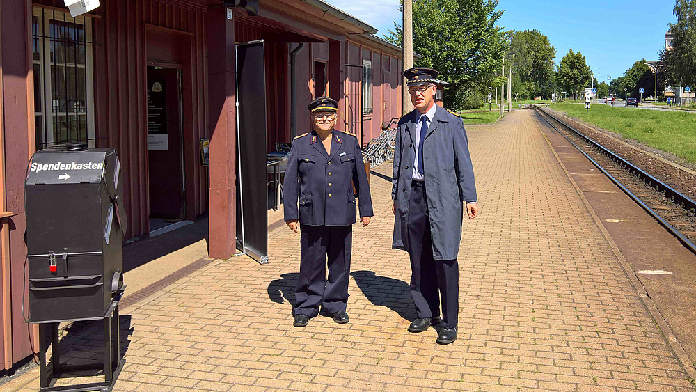 Lehrbeauftragter Hans-Günter Krüger und Laboringenieur Volker Brade vor dem Besucheransturm  in Dienstkleidung der Deutschen Reichsbahn vor dem Bahnhof Zittau Süd