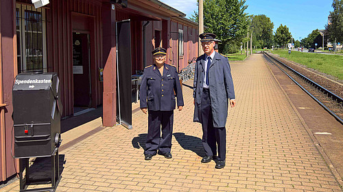Lehrbeauftragter Hans-Günter Krüger und Laboringenieur Volker Brade vor dem Besucheransturm  in Dienstkleidung der Deutschen Reichsbahn vor dem Bahnhof Zittau Süd