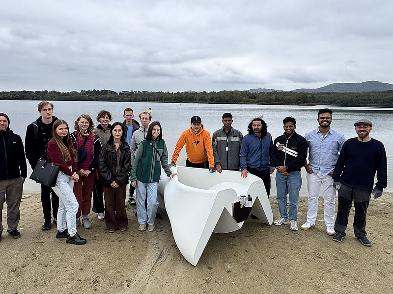 Teilnehmende und Beteiligte der International Summer School mit dem gedruckten Trimaran am Olbersdorfer See.