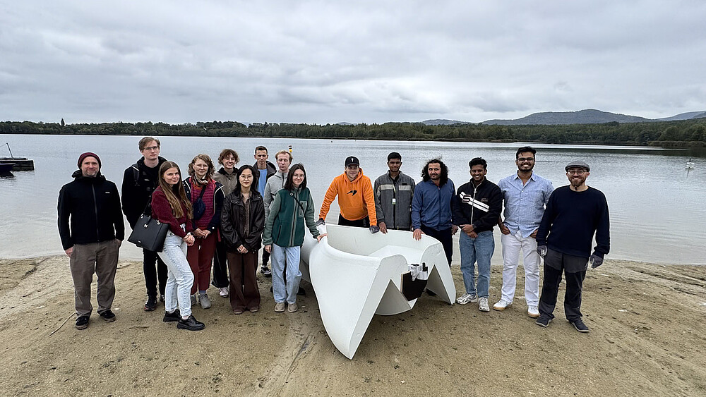 Teilnehmende und Beteiligte der International Summer School mit dem gedruckten Trimaran am Olbersdorfer See.