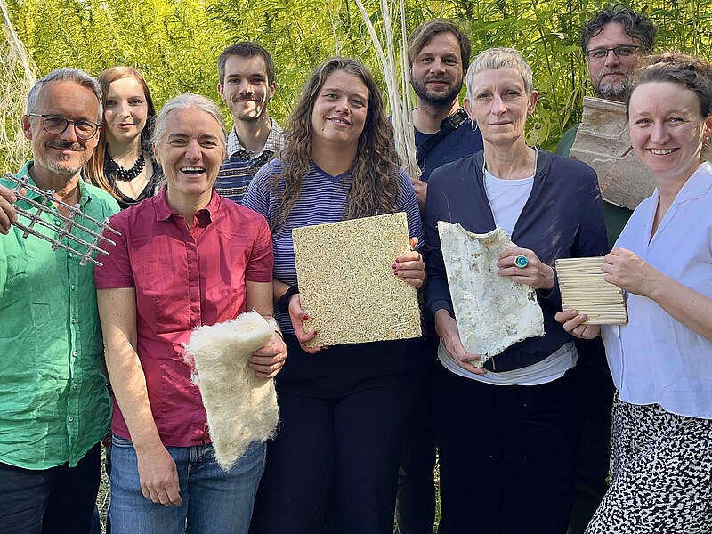 LauTra-Projektteam am Nutzhanf-Versuchsfeld der HSZG mit Naturfasern und daraus gefertigten Beispielprodukten
