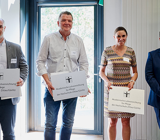 Rector with three cooperation partners in the care sector. They are holding their figurehead and certificate in their hands.