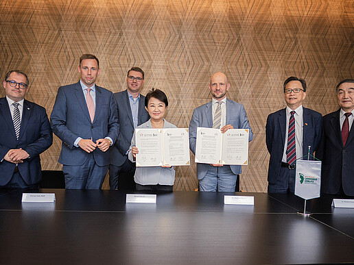 Vertretende aus dem Landkreis Görlitz, Taiwan und der HSZG stehen in einem Sitzungssaal nebeneinander und lächeln in die Kamera, der Landrat und die taiwanesische Vertretung halten das unterzeichnete Memorandum vor sich in die Kamera.