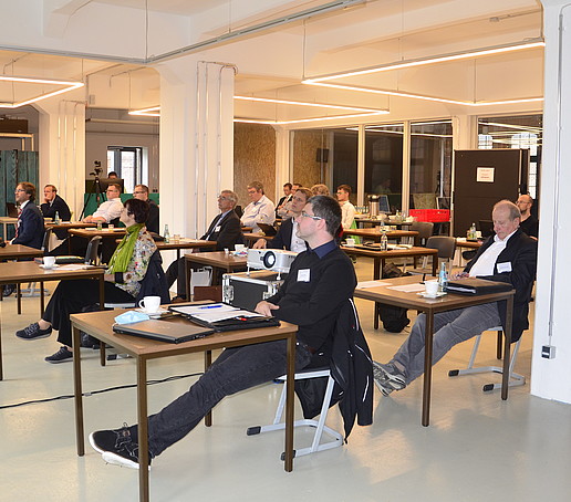 Conference participants sit at individual tables and listen to the presentations.