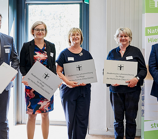 Rector with three cooperation partners in the care sector. They are holding their figurehead and certificate in their hands.