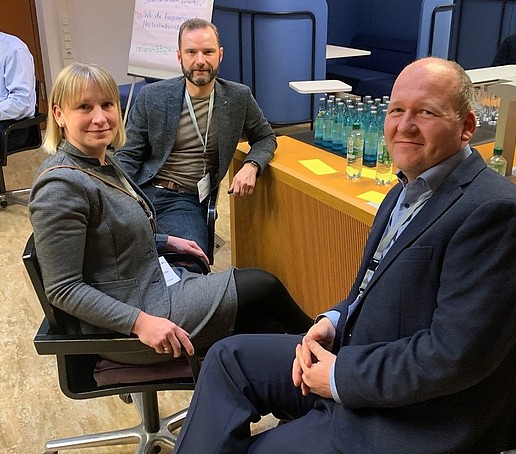 Two men and a woman sitting at a table in a workshop situation