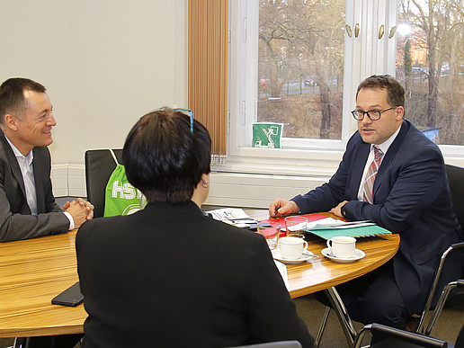 Member of the Bundestag Herbst, Ms. Schütz and the principal are sitting at the table at a meeting.