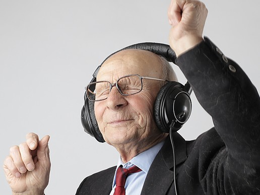 Happy senior citizen with headphones as a symbol for the Master's program in Social Gerontology