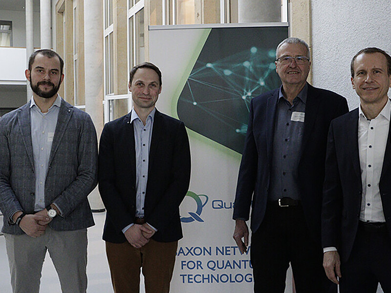 Vier Männer stehen vor einem Roll-up.