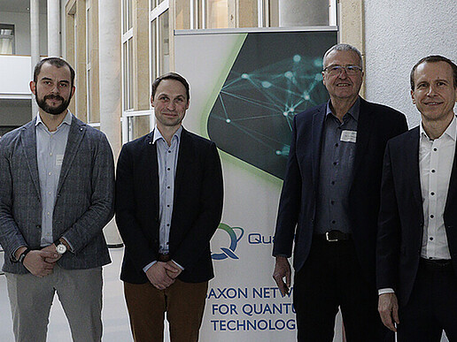 Vier Männer stehen vor einem Roll-up.