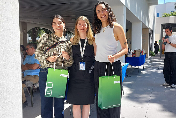 Two women are holding an HSZG gift bag, with Patricia Stange in the middle.