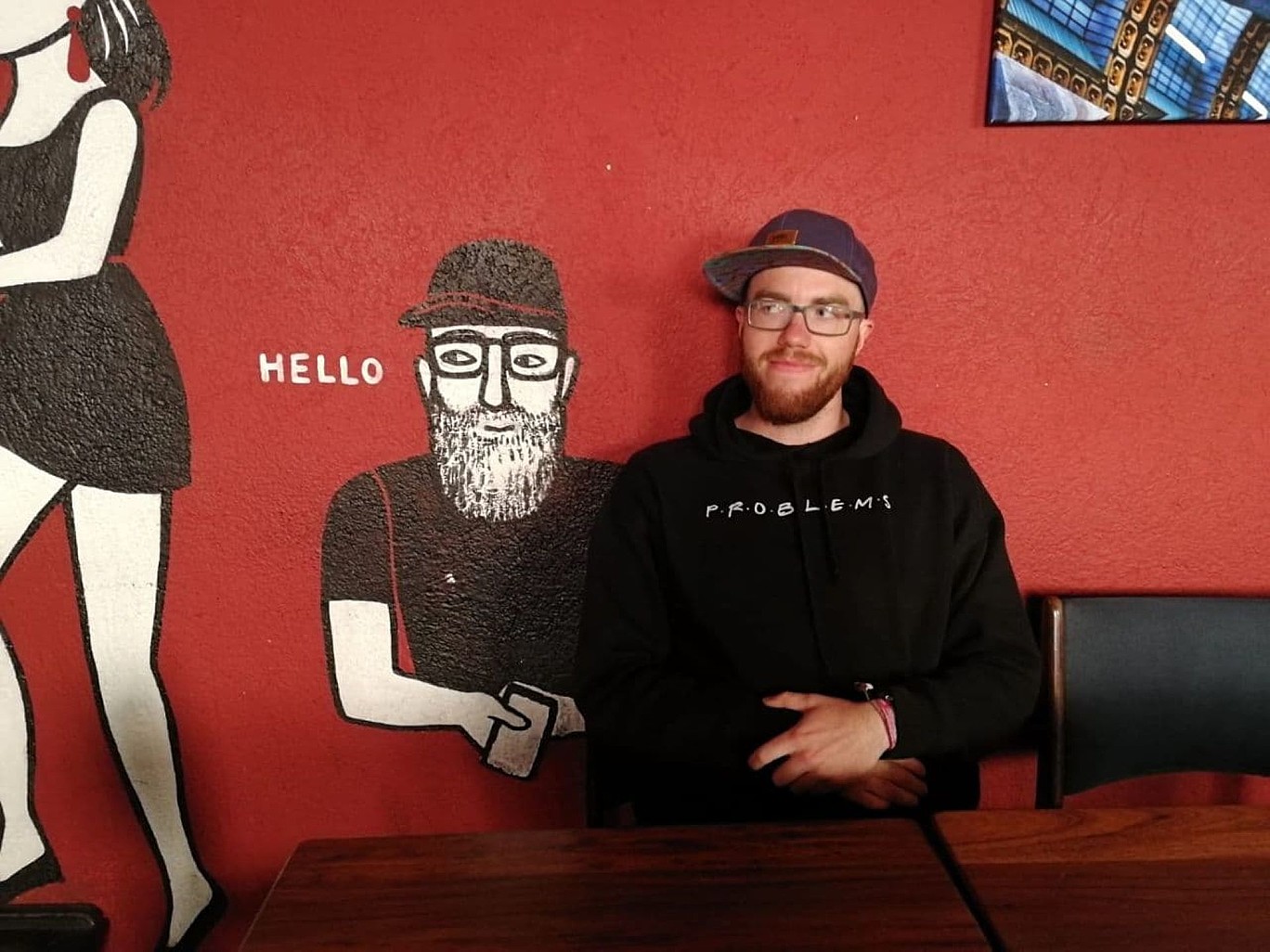 Male person in front of a painted wall with a similar looking male person in this picture