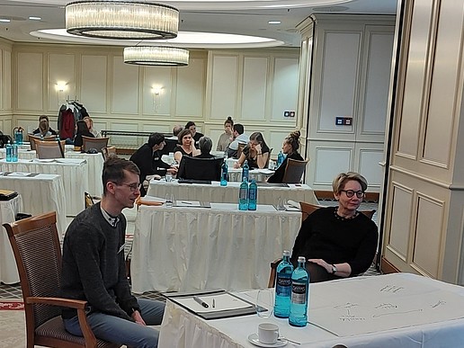 verschiedene Menschen sitzen an Diskussionstischen