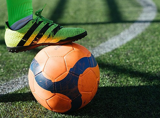Ein Fussball auf dem Rasen mit einem Fußballschuh darauf