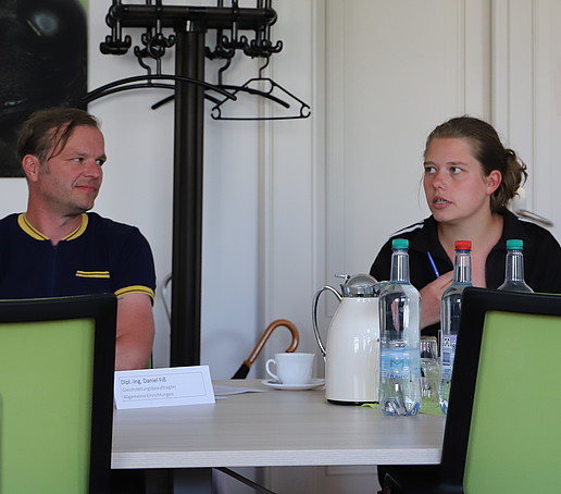 Sitzungsteilnehmende diskutieren miteinander am Tisch im Senatssaal.