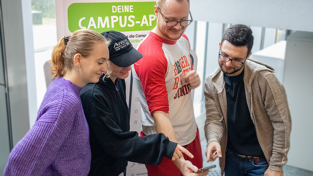 Studierende schauen gemeinsam auf ein Handy.