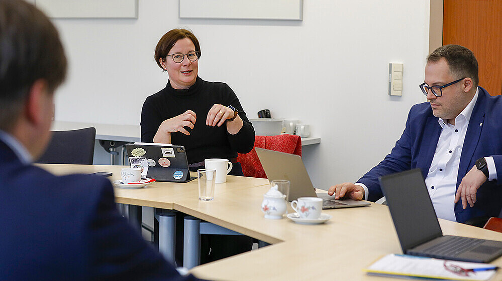 A professor talks to the rector of the HSZG at the table.