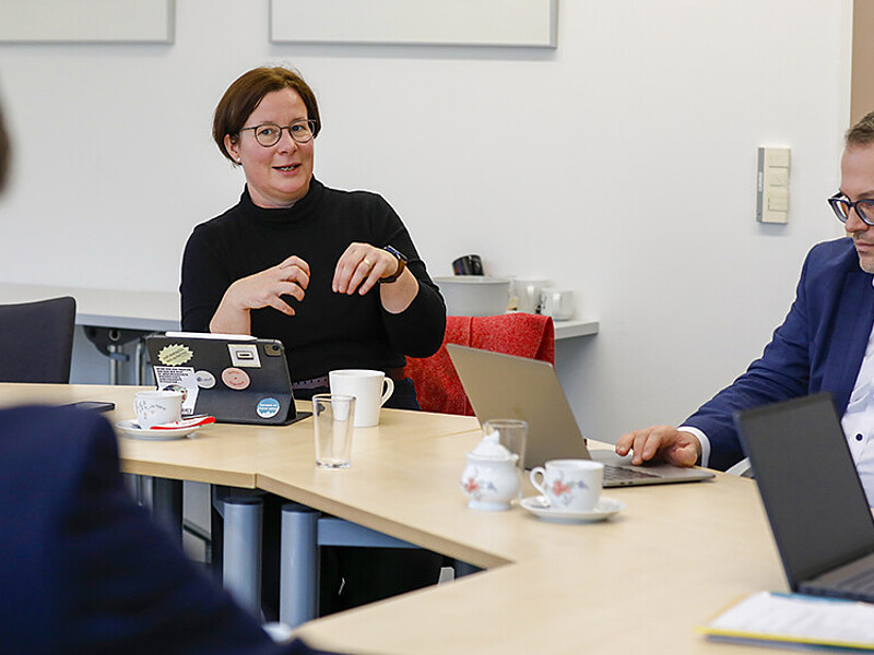 A professor talks to the rector of the HSZG at the table.
